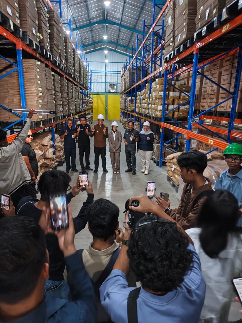 Media crew photographing a group of visitors inside a warehouse